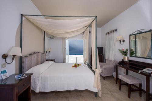 a bedroom with a bed and a desk and a mirror at Aegialis Hotel & Spa in Aegiali