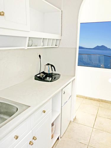 a kitchen with white cabinets and a sink and a window at Aegialis Hotel & Spa in Aegiali