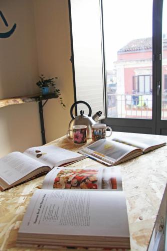 a book on a table with a tea kettle and books at Urban Pop 2 BnB in Catania