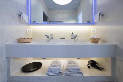 a bathroom with a sink and a mirror and towels at Aegialis Hotel & Spa in Aegiali