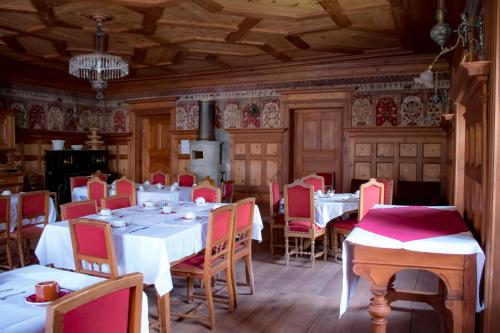 uma sala de jantar com mesas brancas e cadeiras vermelhas em Hotel La Villa della Regina em Gressoney-la-Trinité