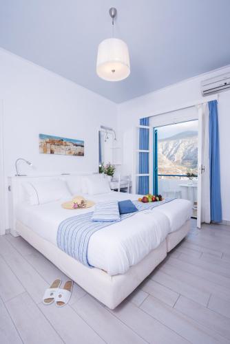 a white bedroom with a large bed and a window at Aegialis Hotel & Spa in Aegiali