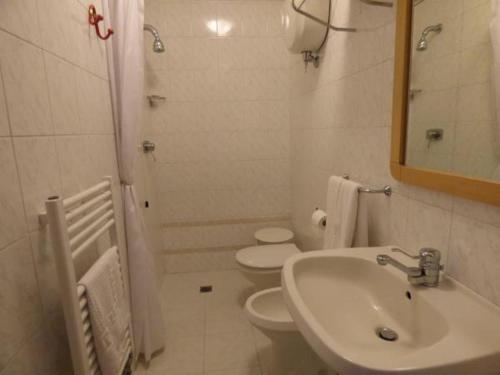 La salle de bains est pourvue d'un lavabo, de toilettes et d'un miroir. dans l'établissement " Il Bersagliere " Dependance Hotel la Pace, à Asciano