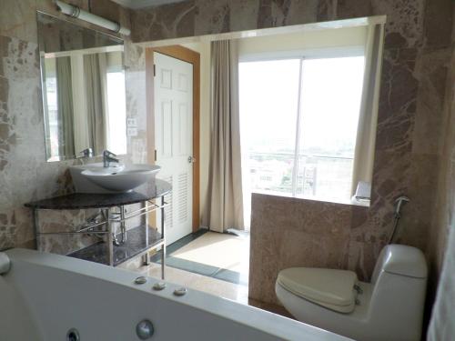 a bathroom with a tub and a sink and a toilet at Westbury Residence in Pattaya South