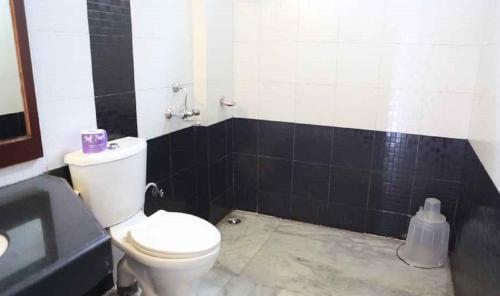 a bathroom with a white toilet and black tiles at Landmark Hills in Shillong