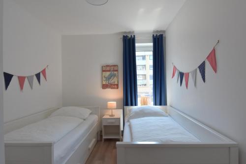 a white bedroom with a bed and a window at Ostseeperle inkl Strandkorb von Mai bis September und Wäsche Set in Heiligenhafen