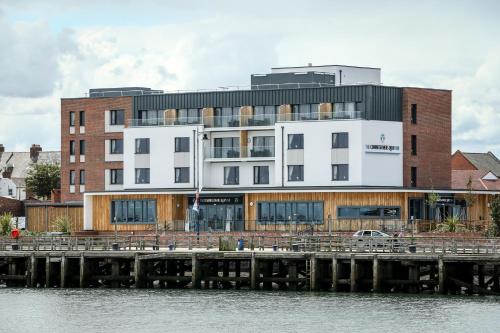 a white building next to a pier next to the water at The Commissioners Quay Inn - The Inn Collection Group in Blythe