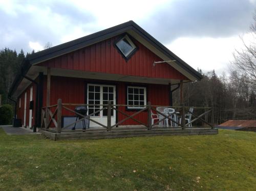 a red barn with a porch on the grass at Berghaga 415 in Ullared