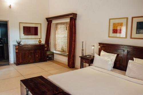 a bedroom with a bed and a desk and a window at Devra Udaipur in Udaipur