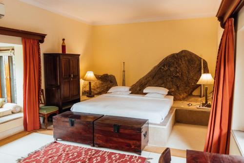 1 dormitorio con 1 cama y 1 roca grande en Devra Udaipur en Udaipur