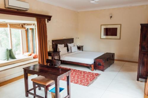 a bedroom with a bed and a desk and window at Devra Udaipur in Udaipur