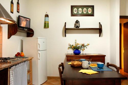 a kitchen with a table and a white refrigerator at Agriturismo Bocci in Castiglione della Pescaia