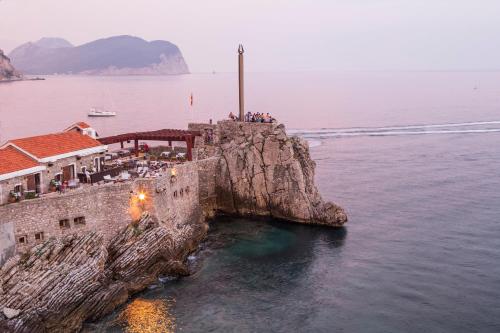 a building on a cliff in the water at Hotel AMI Budva Petrovac in Petrovac na Moru