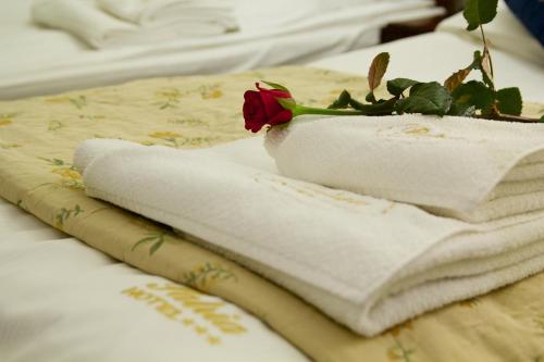 a pile of towels on a bed with a rose at Hotel Patria Zakopane Centrum in Zakopane