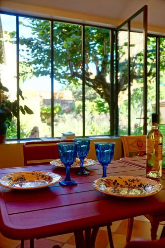 a wooden table with plates and wine glasses on it at La Dommerie-Gite de charme in Domme