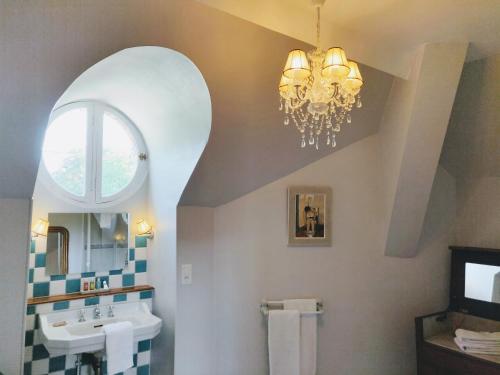 a bathroom with a sink and a chandelier at Domaine de Vauluisant in Courgenay