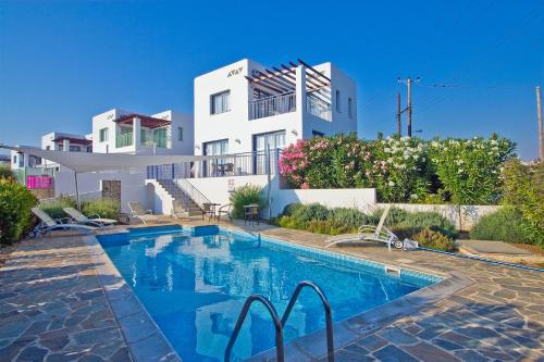 a villa with a swimming pool in front of a house at Meltemi Villas in Paphos City