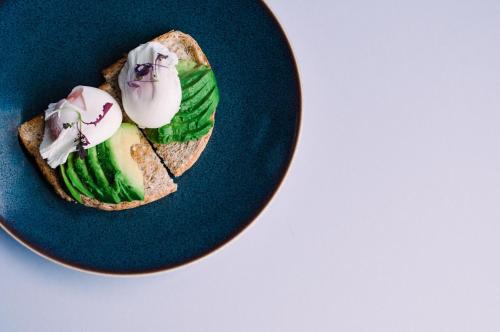 a sandwich on a blue plate with avocado and flowers at Abbey House Hotel in Barrow in Furness