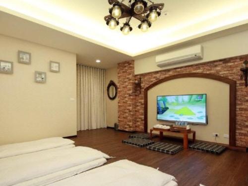 a living room with two beds and a flat screen tv at 來嘉小棧 in Chiayi City