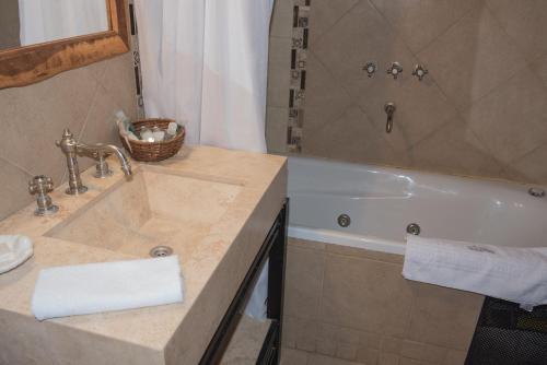 
a bathroom with a sink and a bath tub at La Casa De La Bodega - Wine Boutique Hotel in Cafayate
