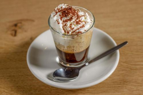 a cup of coffee on a plate with a spoon at Au Bivouac de Napoléon et Spa in Bourg-Saint-Pierre