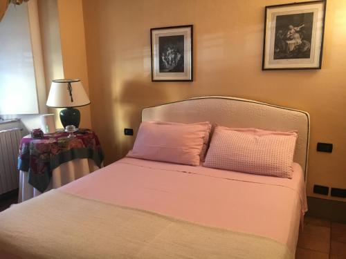 1 dormitorio con 1 cama con sábanas rosas y lámpara en Il Nido Di Tosca, en Lucca