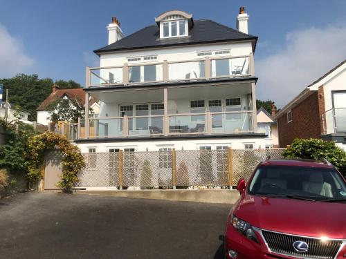 a red car parked in front of a large house at Jurassic View Apartment in Lyme Regis