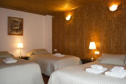 um quarto com três camas com lençóis brancos em Hotel Peretol em Soldeu