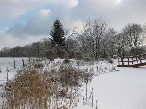 a snow covered field with a fence and a bridge at Urlaubsdomizil im Grünen in Westerstede