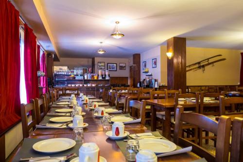 uma longa sala de jantar com mesas e cadeiras de madeira em Hotel Peretol em Soldeu
