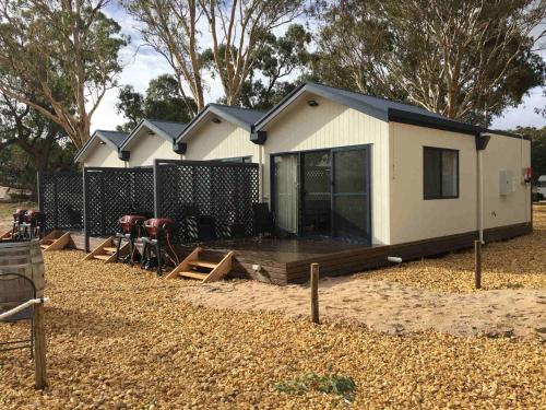 una pequeña casa con una terraza y sillas delante de ella en Coonawarra Ensuite Unit B en Coonawarra