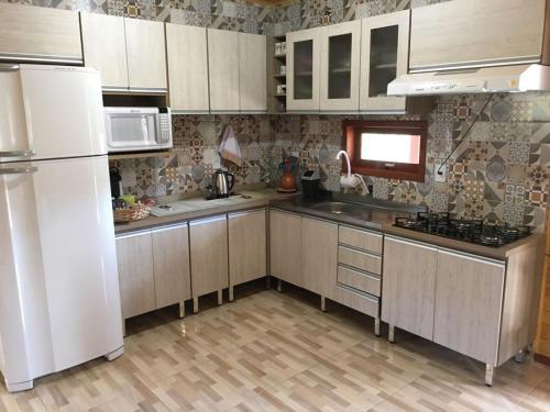 a kitchen with a white refrigerator and a sink at Casa de Campo Vale Rio dos Bugres in Urubici