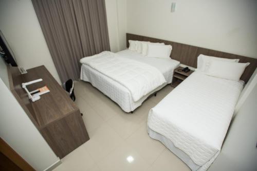 a hotel room with two beds and a table at Sense Hotel Premium in Capinzal