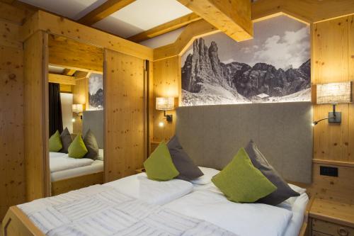 1 dormitorio con 1 cama grande con almohadas verdes en Hotel Cirelle Suite & Spa, en Canazei