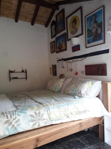 a bedroom with a wooden bed with paintings on the wall at Jacamaki Nature GuestHouse en Villa de Leyva in Villa de Leyva