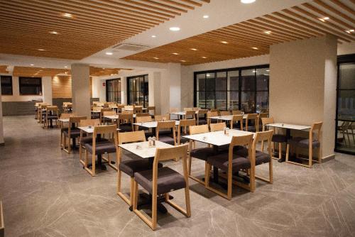a restaurant with wooden tables and chairs and windows at Pefkos City Hotel in Limassol