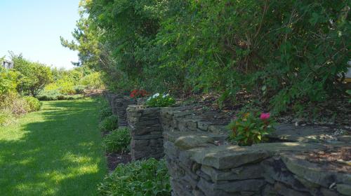 a stone retaining wall in a garden with flowers at Sea Crest in Amagansett