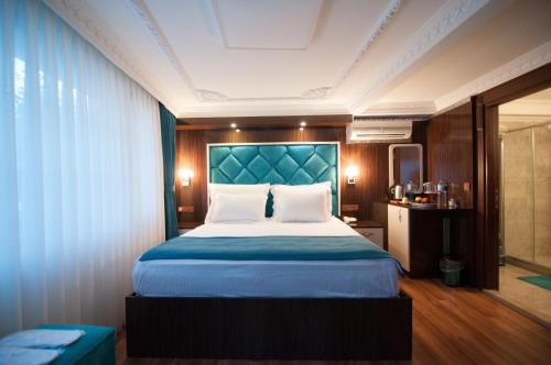 une chambre avec un grand lit et une tête de lit bleue dans l'établissement Akbiyik Suite Boutique Hotel, à Istanbul