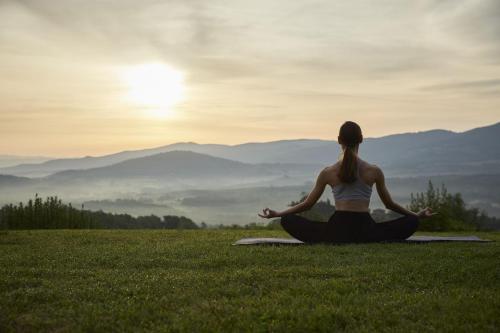 a woman in a field doing yoga on the grass at Castello di Casole, A Belmond Hotel, Tuscany in Casole dʼElsa