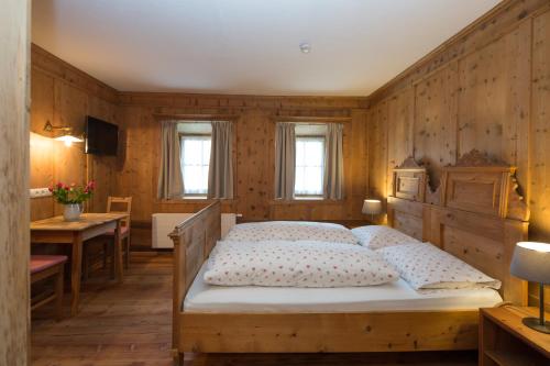 a bedroom with a bed with a wooden wall at Garni Bachlerhof in Brunico