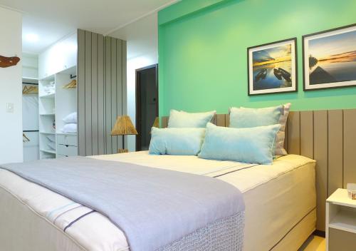 a bedroom with a large bed with blue walls at Excelentes apartamentos Barra Bali in Barra de São Miguel