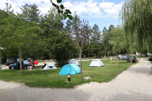 a group of tents in a park with parked cars at Camping La Ferme de Castellane in Castellane