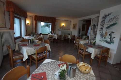 a restaurant with tables and chairs in a room at Garni Miravalle in Moena