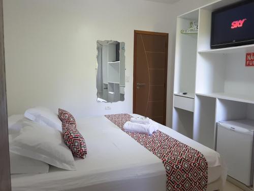 a room with a bed with a tv on the wall at Pousada Morro do Pico in Fernando de Noronha