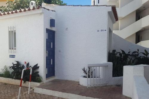 a white building with a blue door and some plants at Apartamentos Turisticos Soldoiro in Albufeira