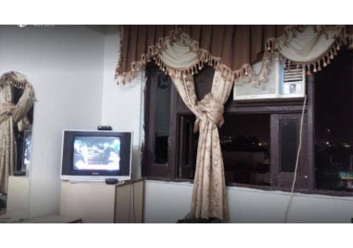 a room with a window with curtains and a television at D.C hotel in Chittaurgarh