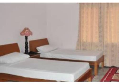 Cette chambre comprend deux lits et une lampe sur une table. dans l'établissement D.C hotel, à Chittorgarh