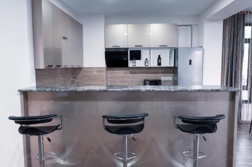 a kitchen with a bar with three stools at Avlabari Terrace Rooms in Tbilisi City