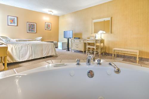 a bathroom with a bath tub and a bedroom at Hotel Motel Penn-Mass in Trois-Rivières