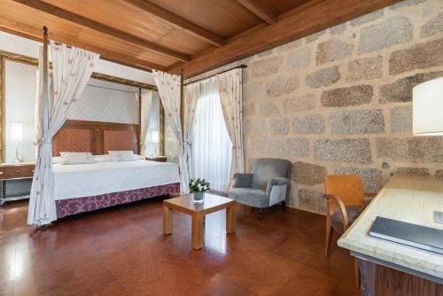 Un dormitorio con una cama y una pared de piedra. en Eurostars Monumento Monasterio de San Clodio Hotel, en Leiro